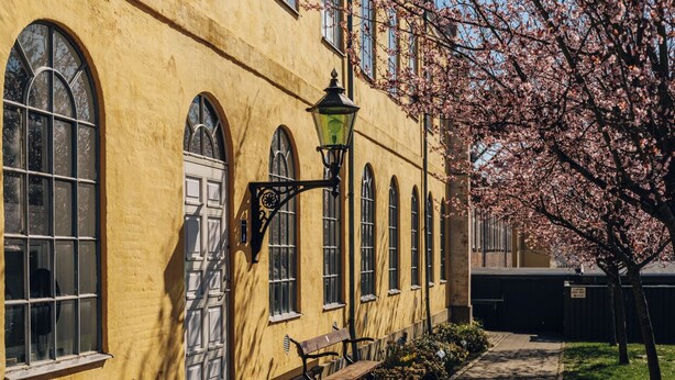 A yellow building with arched windows and a bench outside. - Stoeberiet (Svendborg)