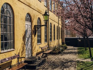 A yellow building with arched windows and a bench outside. - Stoeberiet (Svendborg)