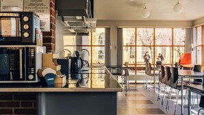 A modern cafe with a brick wall, a coffee machine, and a large window with a view of people outside. - Stoeberiet (Svendborg)