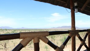 A wooden balcony with a view of a desert landscape.