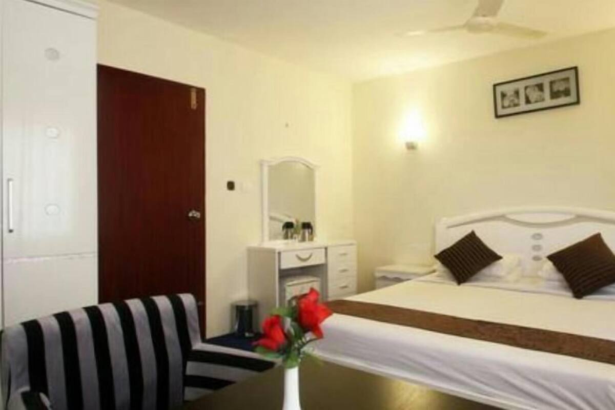 A hotel room with a bed, bedside table, nightstand, dresser, mirror, and a striped chair.