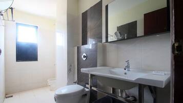 A modern bathroom with a white sink, a mirror, and a toilet.