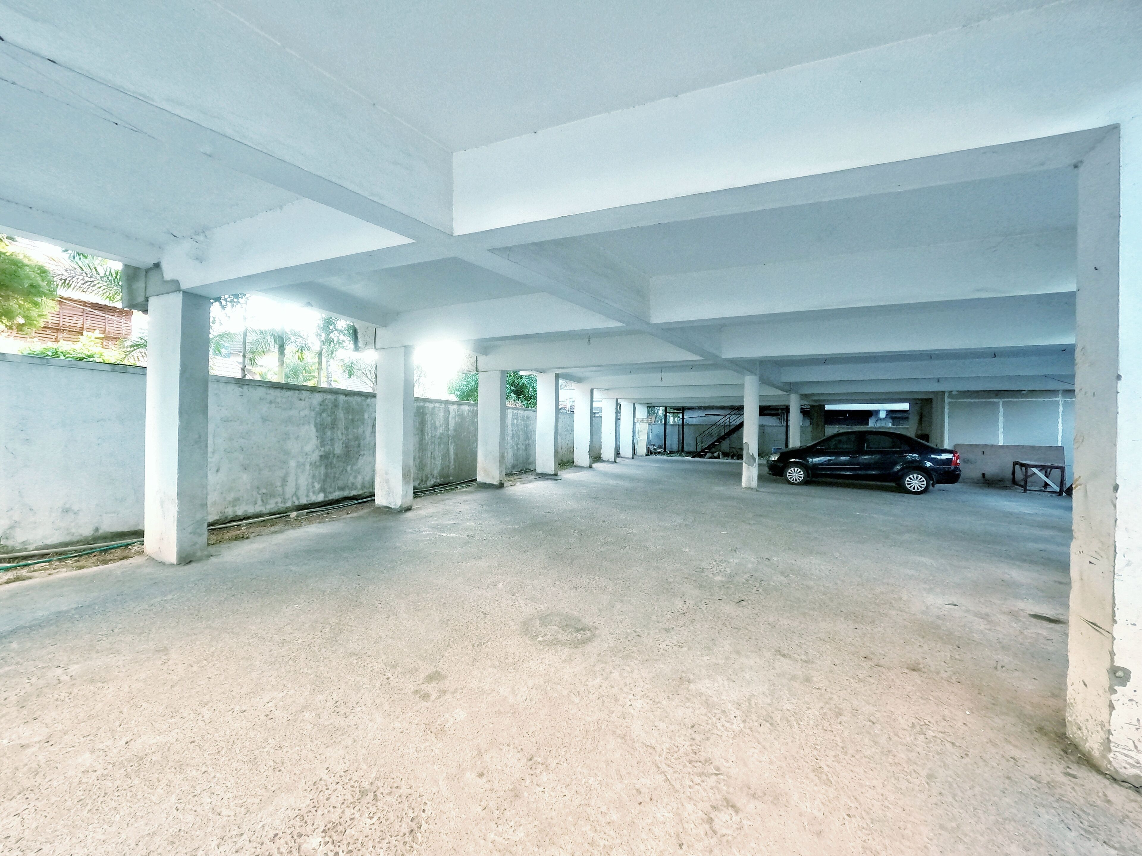 An empty parking garage with concrete pillars and a single parked car.