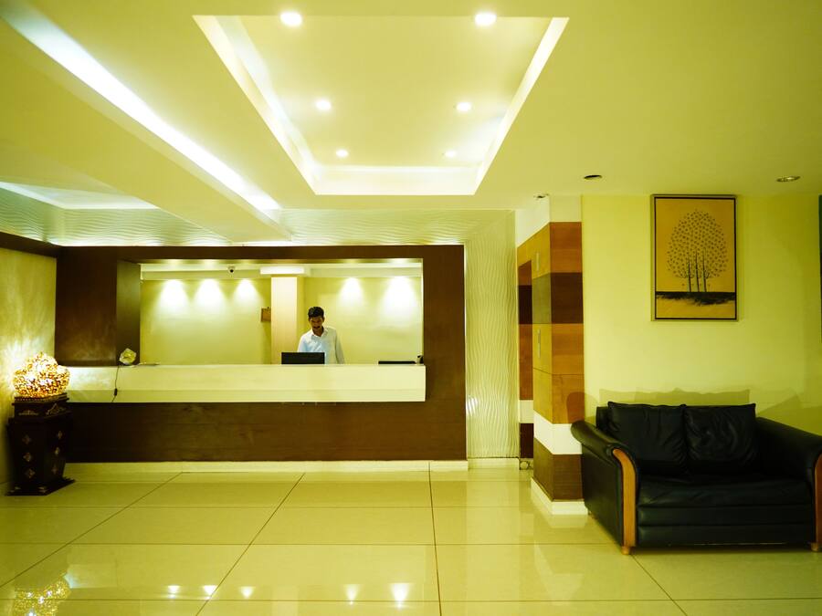 Un espace d’accueil d’hôtel comprenant un comptoir de réception, un canapé en cuir noir et une œuvre d’art encadrée accrochée au mur.