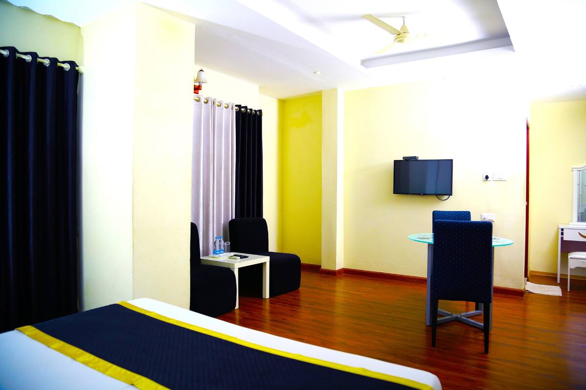 A hotel room with a bed, a desk, a chair, a television, and a small table.
