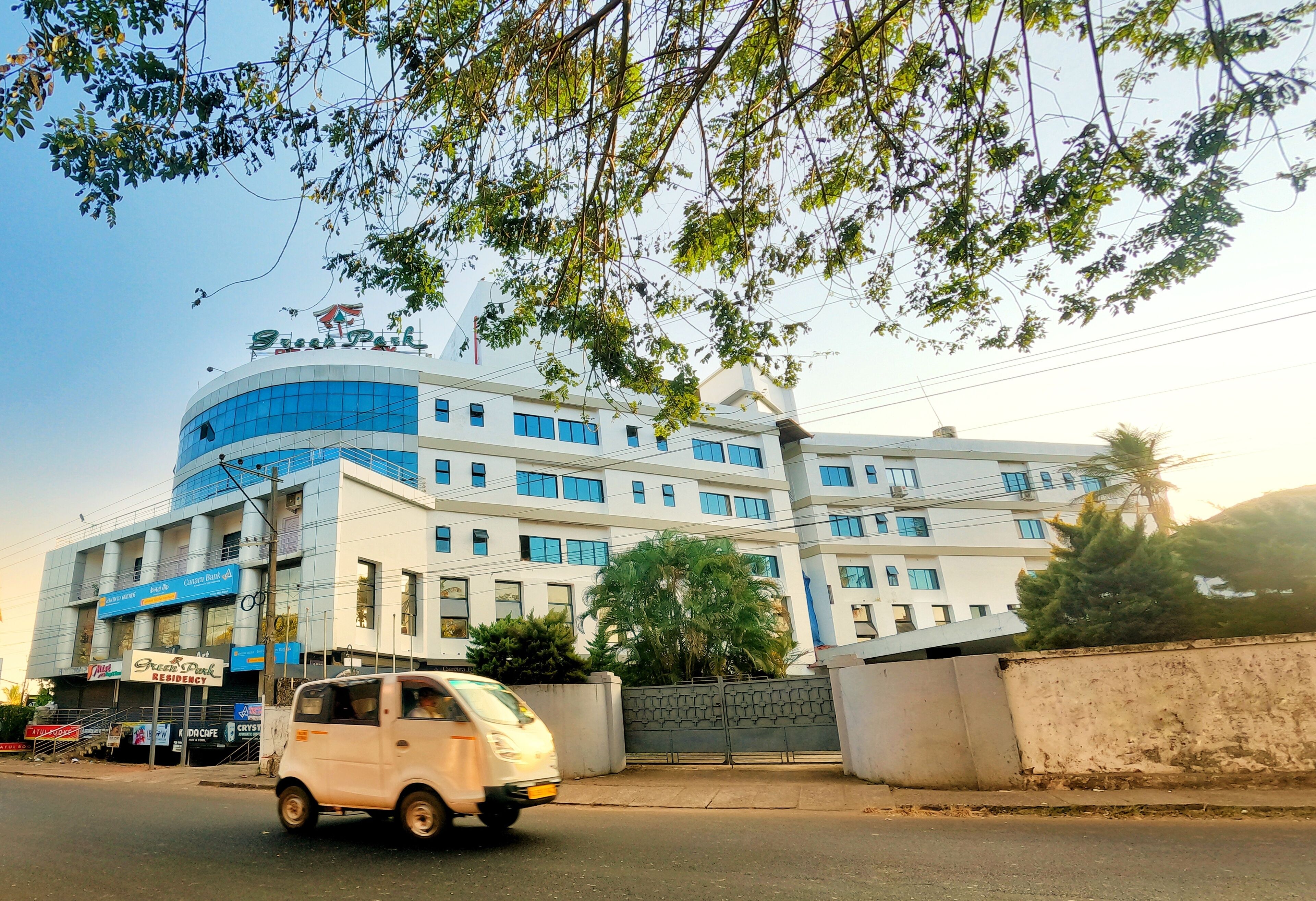 A multi-story building with a curved facade, large windows, and a sign for 'Green Park Residency'.