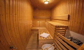A wooden sauna with benches and a bench seat, a towel, and a bucket. - Hotel Im Schwedischen Hof (Binz)