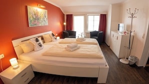 A hotel room with a large bed, bedside tables, a desk, and a chair.