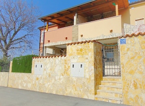 A two-story house with a stone facade, a wooden balcony, and a gated entrance. - Segundo al Mar Apartments (Medulin)