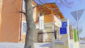 A building with a stone facade, a metal gate, and a blue sign indicating the address and type of accommodation. - Segundo al Mar Apartments (Medulin)