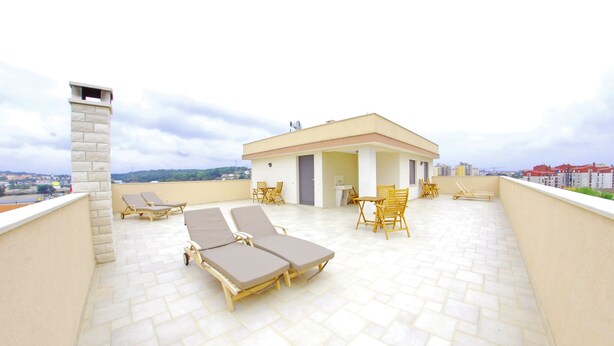 Une terrasse sur le toit, dotée de chaises longues, un petit bâtiment et une vue sur la ville.