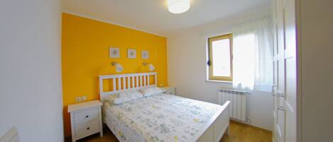A bedroom with a bed, nightstands, a window, and a radiator.