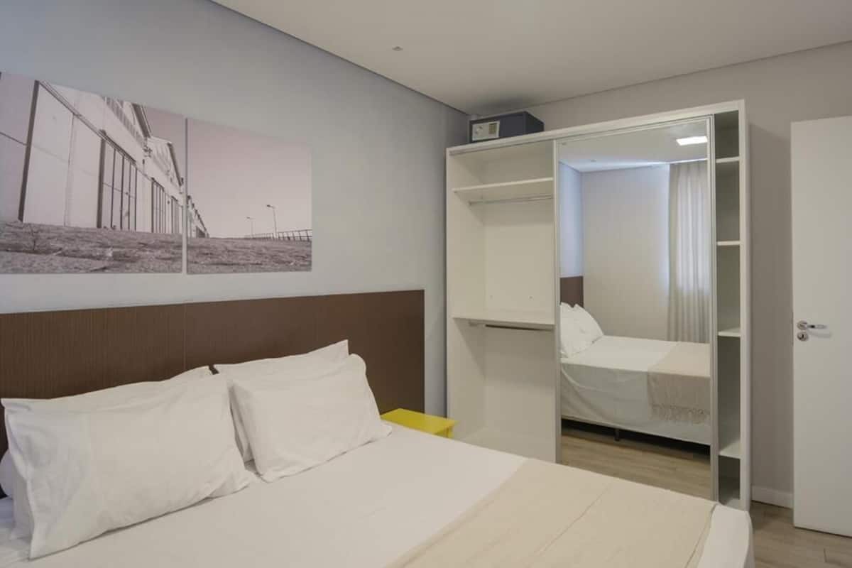 Quarto de hotel com cama, guarda-roupa e espelho.