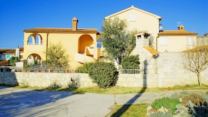 A two-story building with a yellow facade, stone walls, and a tiled roof. - Sol Jardin Apartments (Medulin)