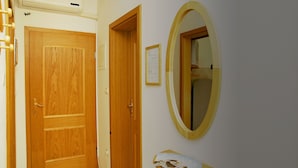 A hallway with a wooden door, a framed notice, and a mirror on the wall. - Sol Jardin Apartments (Medulin)