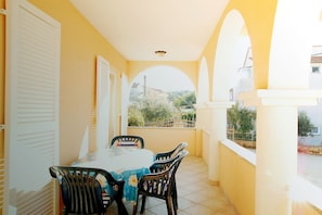 A balcony with a table and chairs, a view of greenery and buildings, and a yellow wall. - Sol Jardin Apartments (Medulin)