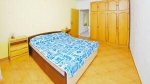 A bedroom with a bed, wooden wardrobe, and a nightstand. - Storia di Mare Apartments (Rasa)