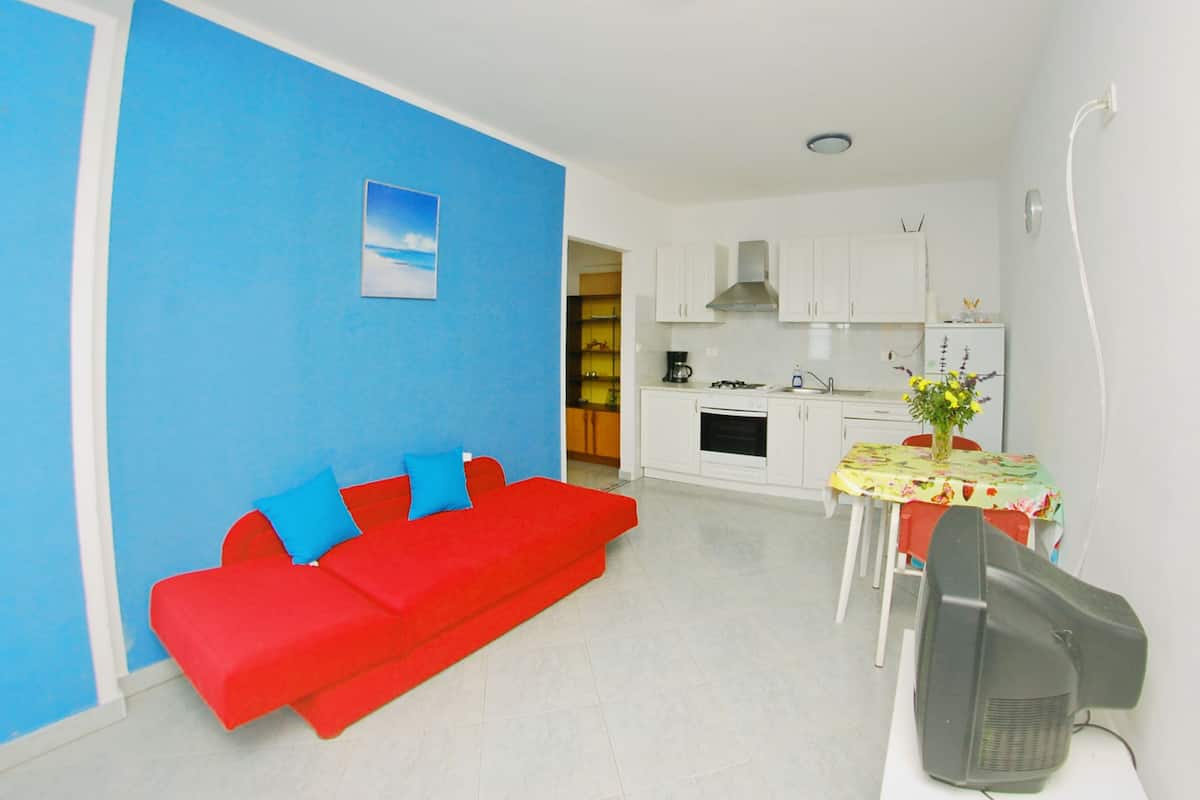 A living room with a red sofa and a dining area with a table and chairs.