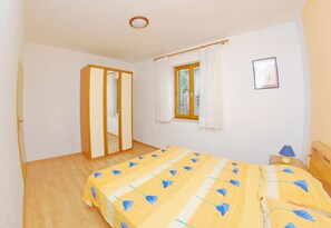 A bedroom with a bed, a wardrobe, a window, and a nightstand.
