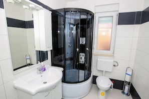 A modern bathroom with a glass-enclosed shower, a white sink, and a toilet. - Vodopija Apartments (Porec)