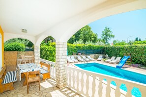 A covered outdoor swimming pool area with lounge chairs, a table, and a slide. - Vacation Pool Apartments (Sveta Nedelja)