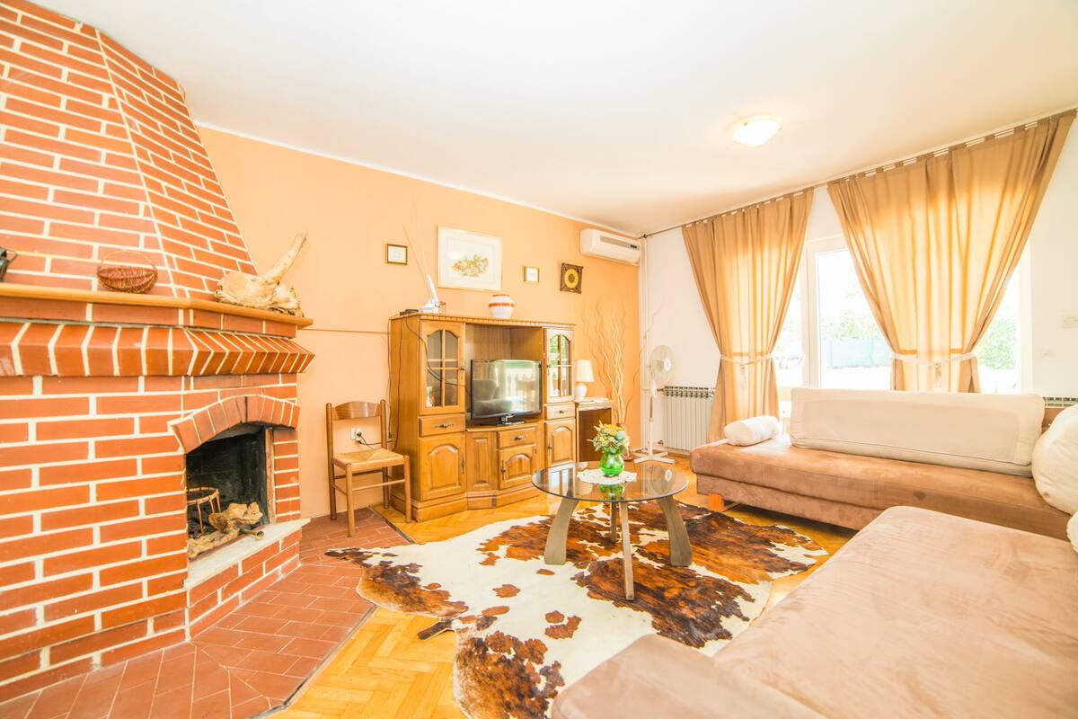 Un salon avec une cheminée en briques, un canapé, une table basse en verre et un tapis en peau de vache.
