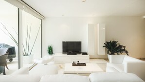 A modern living room with a flat-screen TV, white sofas, a coffee table, and a large window. - Elements GH8 by NAS (Playa del Carmen)