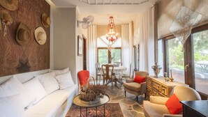 A cozy living room with a sofa, chairs, a dining table, and a chandelier. - Alterra Vita (Sithonia)