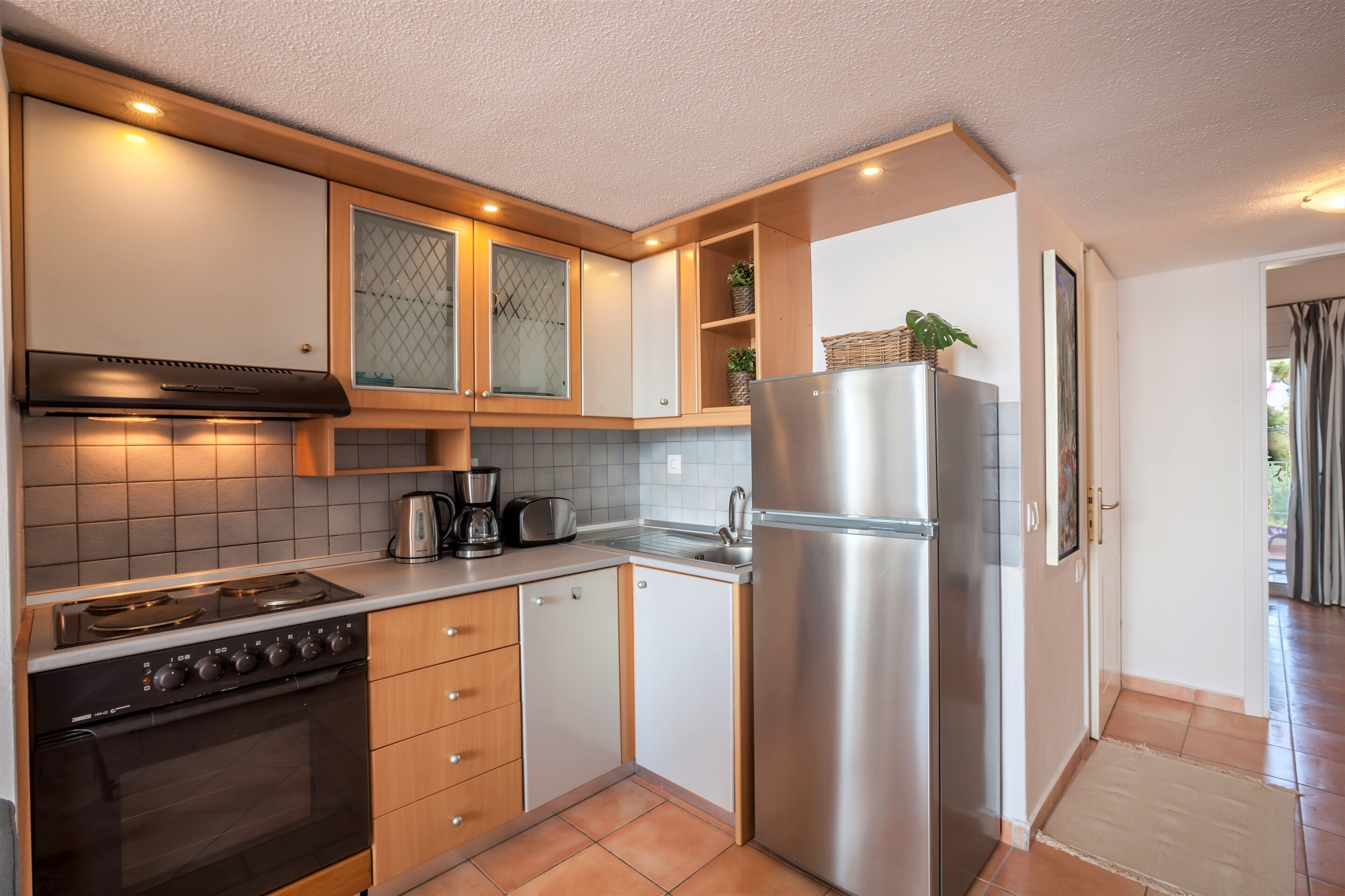 A compact kitchen with a stove, oven, refrigerator, and a sink.