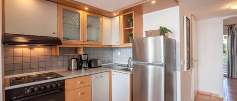 A compact kitchen with a stove, oven, refrigerator, and a sink.
