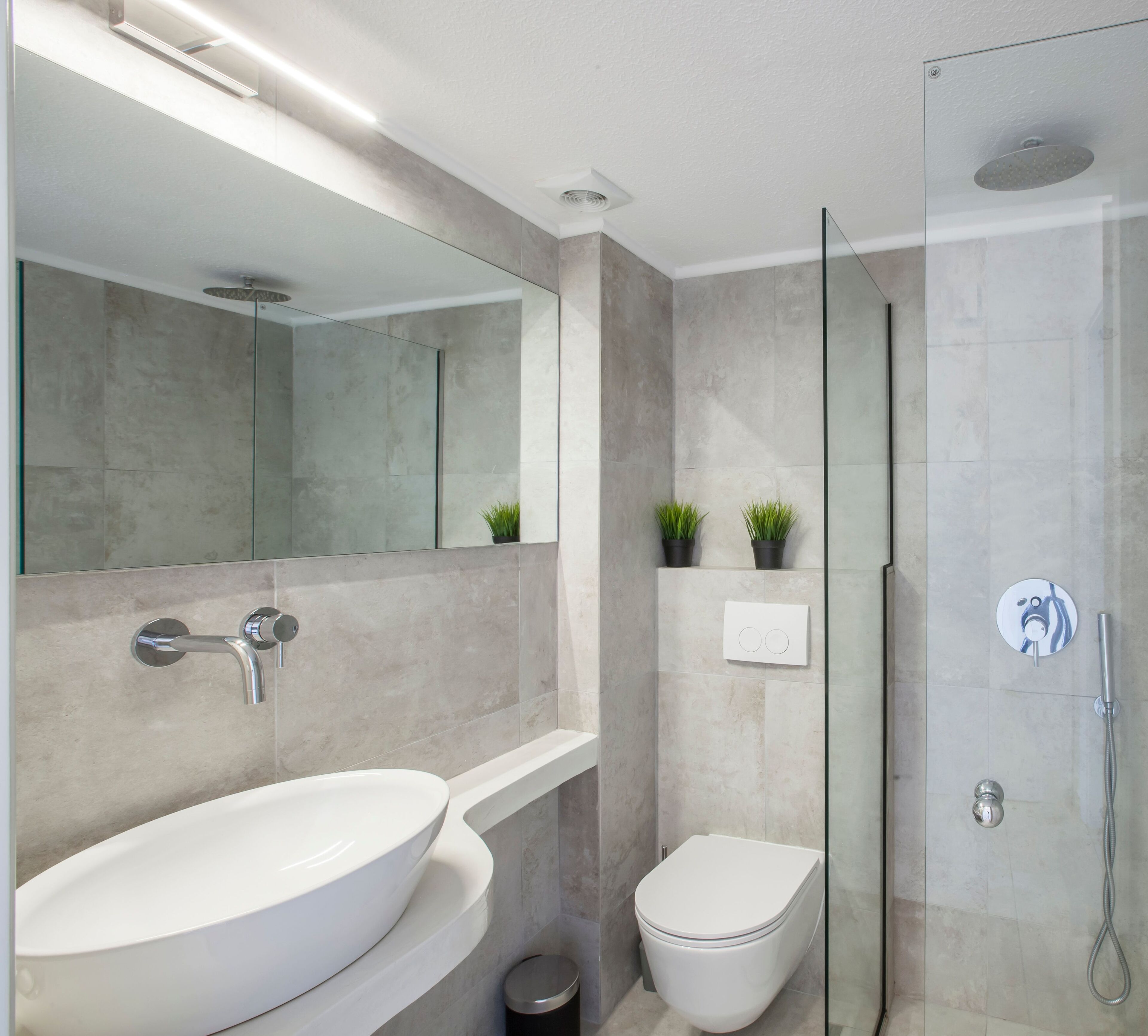 Un bagno moderno con un lavandino ampio, uno specchio e cabina doccia in vetro.