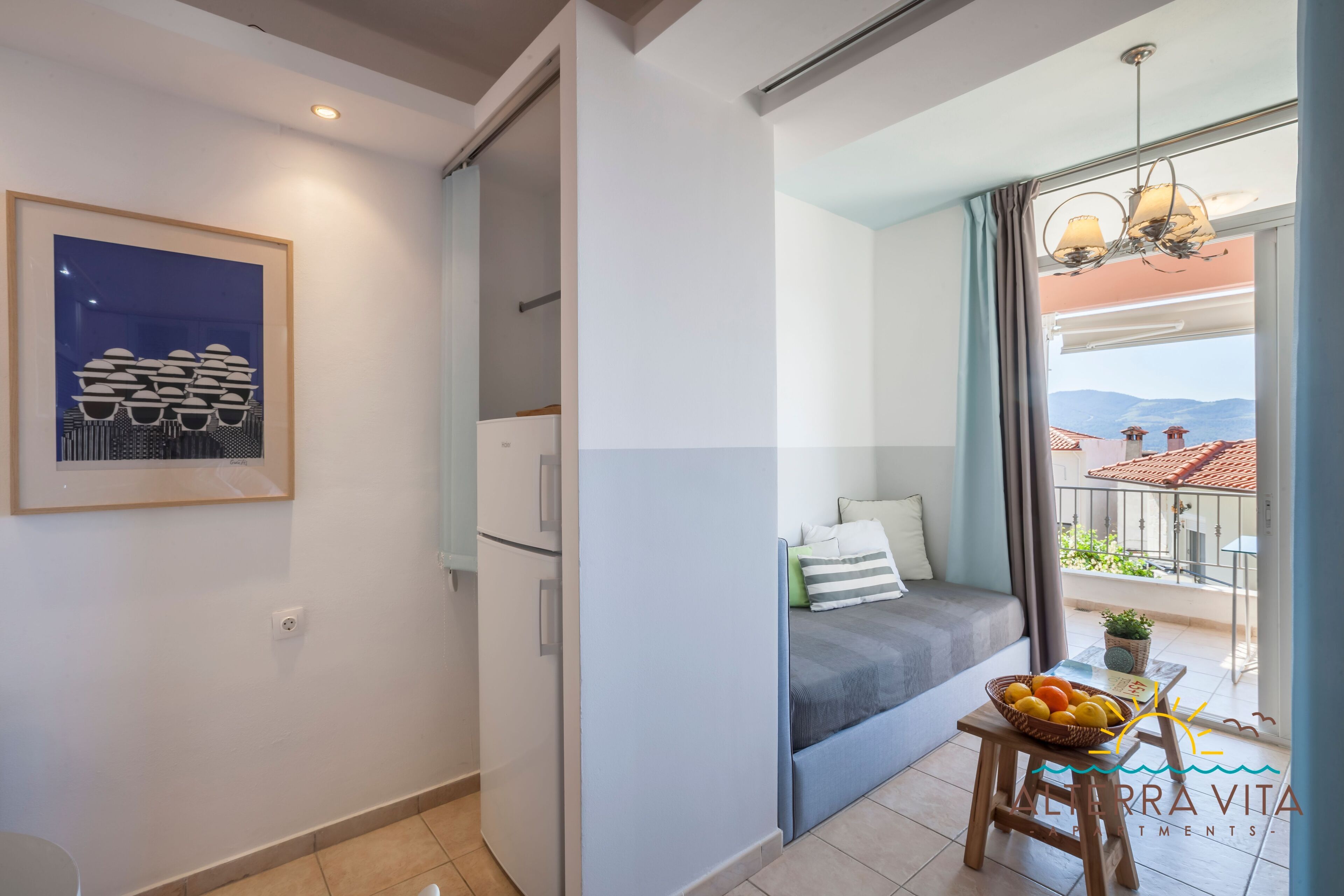 A modern apartment with a balcony, a dining area with a fruit bowl, and a framed artwork on the wall.