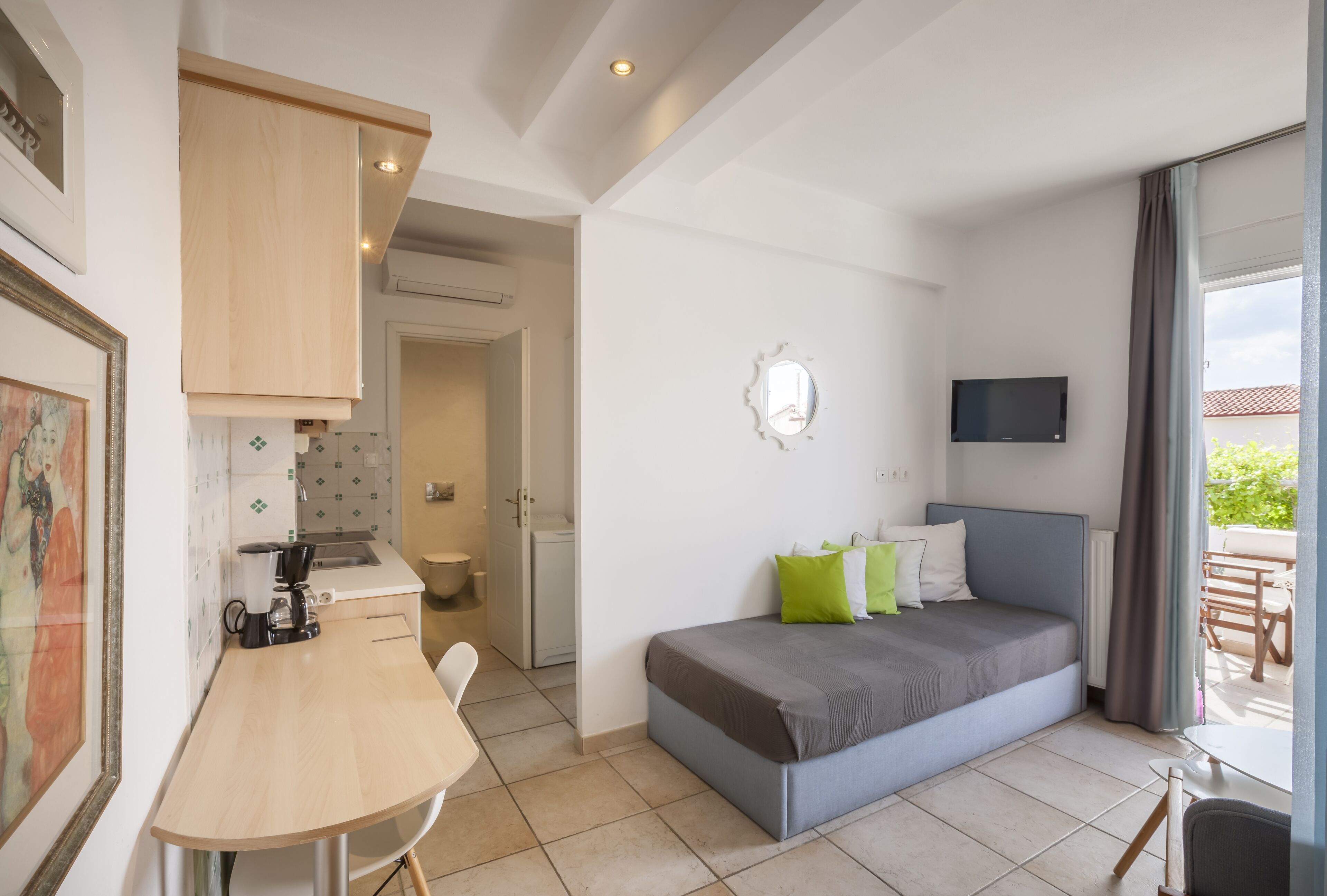 Une chambre moderne équipée d’un lit, d’une télévision, d’un bureau et d’une kitchenette.