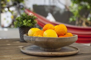 A wooden bowl filled with oranges on a wooden table. - Alterra Vita Apartments (Sithonia)