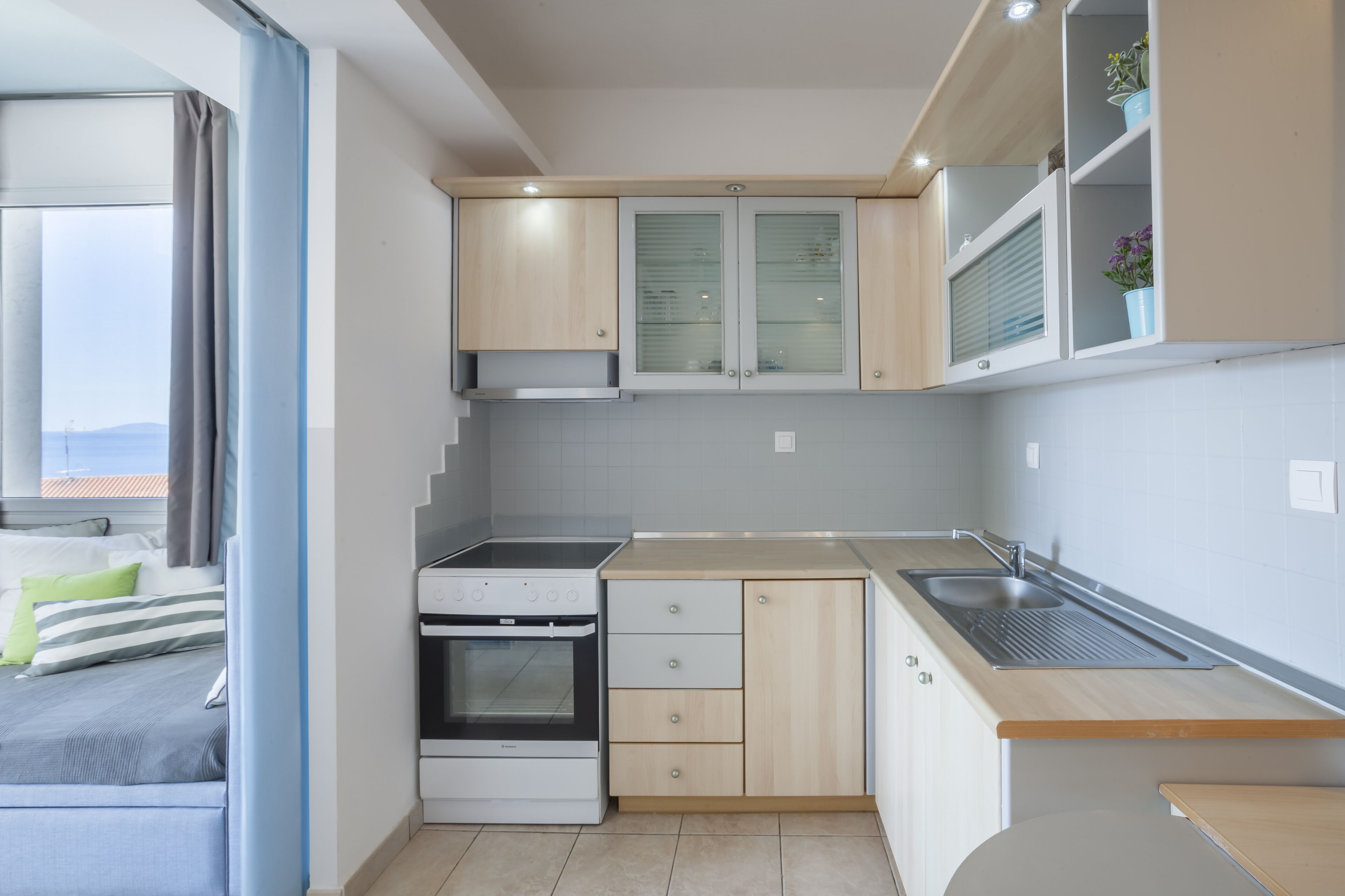 A compact kitchen with a stove, sink, and cabinets.