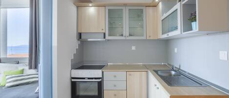 A compact kitchen with a stove, sink, and cabinets.