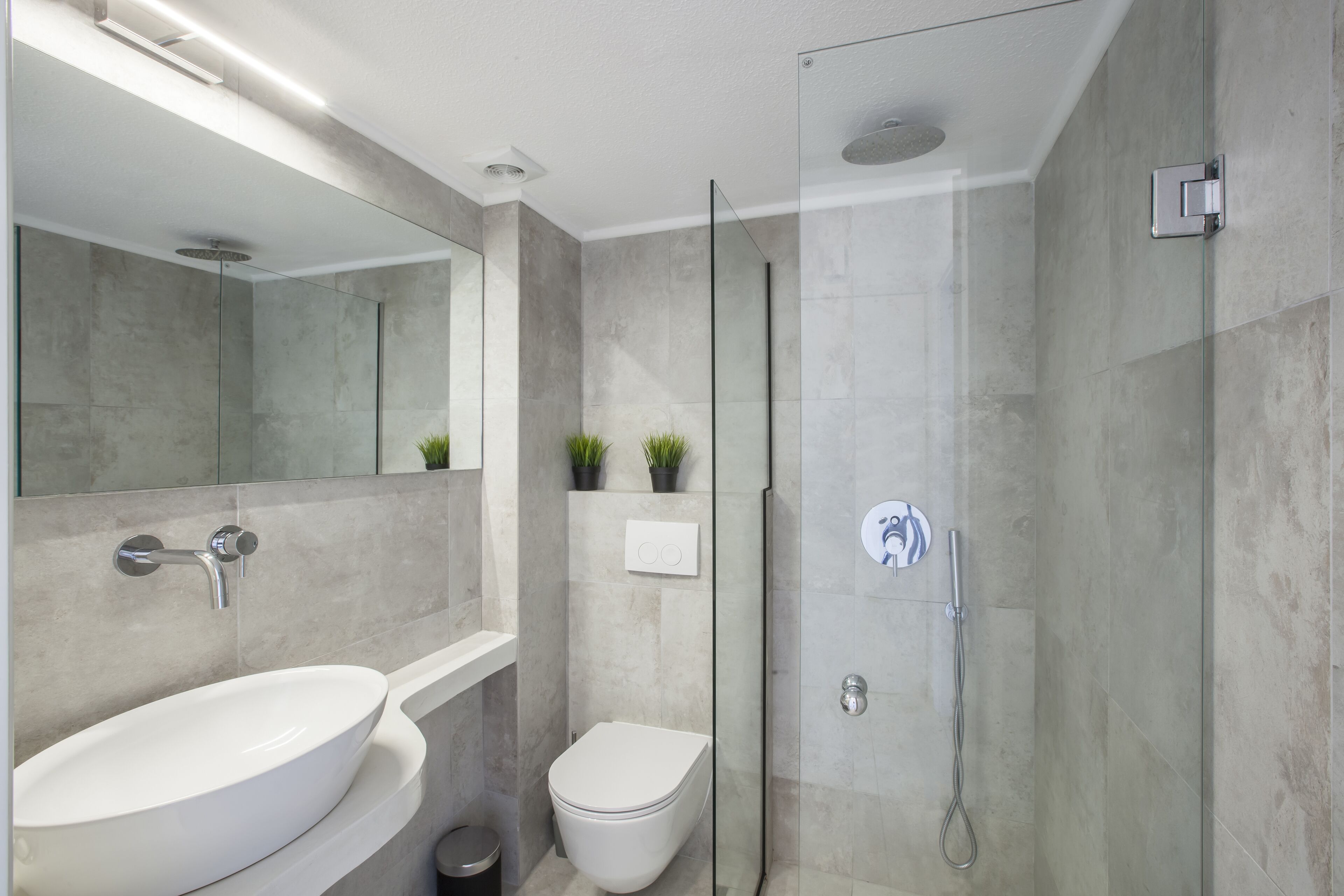 A modern bathroom with a large sink, toilet, and glass-enclosed shower.