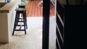 Un espace patio avec une terrasse en bois, une petite table et deux tabourets.