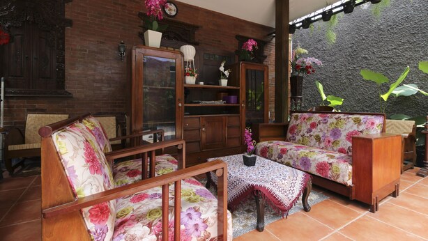 Un salón acogedor con muebles de madera, un sofá floral y una mesa de centro con mantel de encaje.