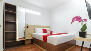 Un dormitorio con cama, mesita de noche, armario, espejo y una orquídea en maceta.