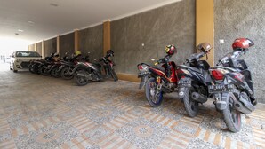 Un área de estacionamiento techada con varias motocicletas y un automóvil.