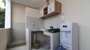 Cocina compacta con estufa a gas integrada, dispensador de agua y una botella de agua grande.