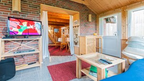 Une pièce confortable avec une télévision, des meubles en bois et une moquette rouge.