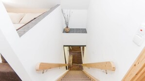 Un escalier avec une rampe en bois, un petit vase décoratif accroché au mur et un interrupteur sur le mur.