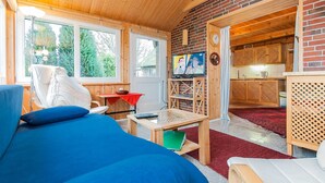 Un intérieur de chalet chaleureux comprenant un lit, un téléviseur, un coin repas et une cuisine.