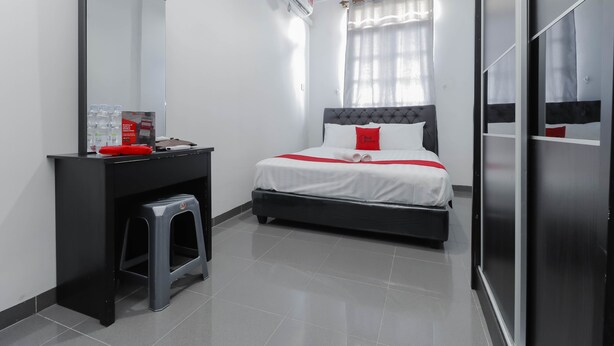 A modern bedroom with a bed, a vanity with a mirror, and a stool. - RedDoorz Plus near Batam City Square (Batam)