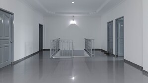 A hallway with a polished floor, white walls, and a ceiling light. - RedDoorz Plus near Batam City Square (Batam)