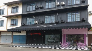 A two-story building with a black awning, large windows, and air conditioning units. - RedDoorz Plus near Batam City Square (Batam)