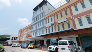 A multi-story building with a ground-level commercial space and a parking area. - RedDoorz @ Nagoya Indah (Batam)