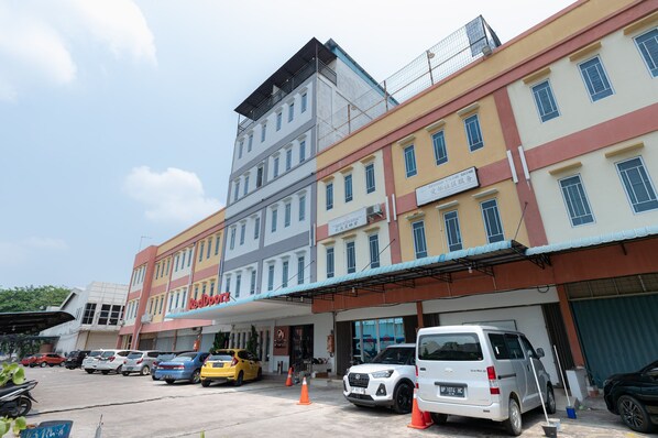 A multi-story building with a ground-level commercial space and a parking area. - RedDoorz @ Nagoya Indah (Batam)